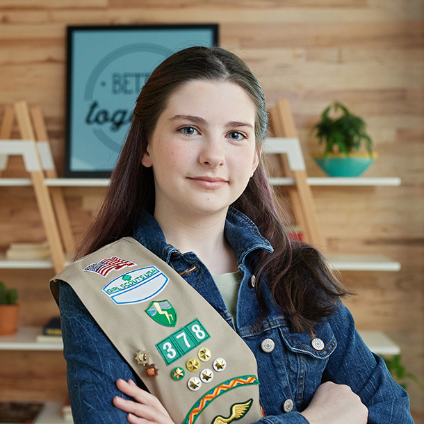 ambassador high school girl scout wearing sash outside against green background